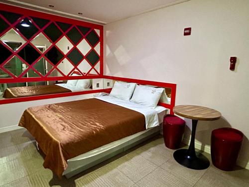 a bedroom with a bed with a red headboard and a table at Two motel in Tongyeong