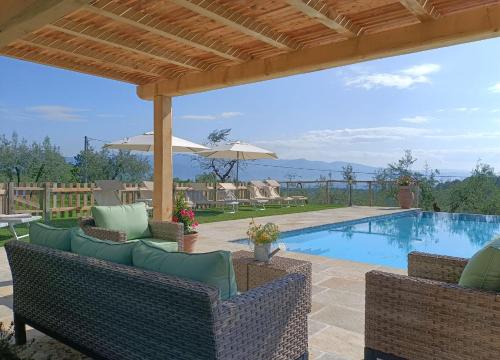 un patio con piscina, sillas y sombrilla en Villa Claudia, en Cavriglia
