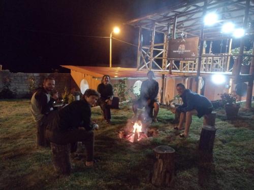 a group of people sitting around a fire at night at the wooden house choquequirao in Cachora