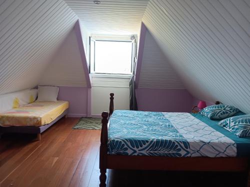 a attic bedroom with two beds and a window at Les Villas Créoles de Sainte-Anne in Sainte-Anne