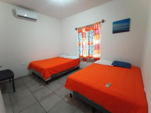 Habitación con 2 camas, escritorio y ventana. en CASA PARLAMAR, en Monterrico