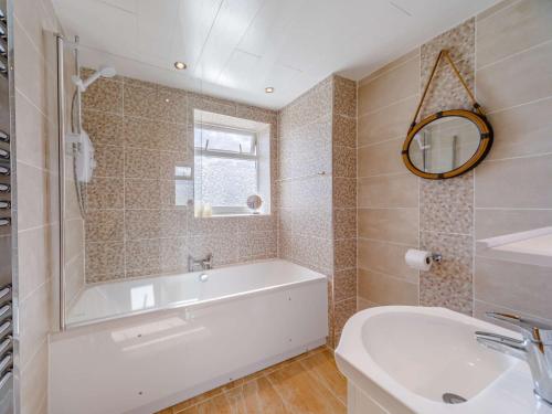 a bathroom with a tub and a sink and a mirror at 3 Bed in Seahouses 86834 in North Sunderland