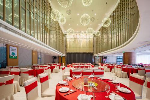 un gran salón de banquetes con mesas rojas y sillas blancas en Sunshine Holiday Hotel Fuzhou, en Fuzhou