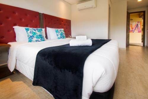 a bedroom with a large white bed with a red headboard at Hotel Barra da Lagoa by Latitud Hoteles in Búzios