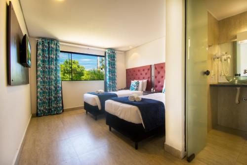 a hotel room with two beds and a window at Hotel Barra da Lagoa by Latitud Hoteles in Búzios