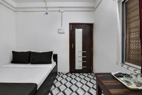 a room with a bed and a table and a door at Super OYO PPS NEST Guest House in Kolkata