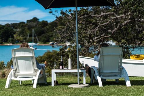 two people sitting in lawn chairs under an umbrella at Boatsheds on the Bay, Waiheke Island in Ostend
