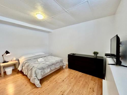 a white bedroom with a bed and a television at Auberge Chez Moi Chez Toi in Val-dʼOr