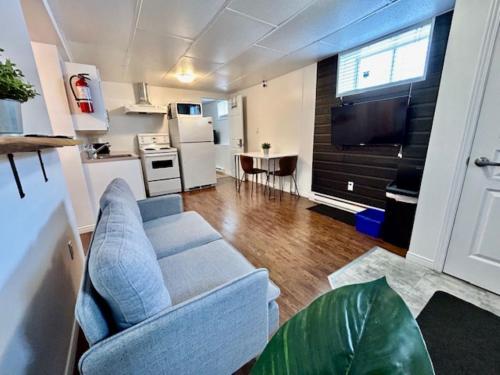 a living room with a couch and a kitchen at Auberge Chez Moi Chez Toi in Val-dʼOr