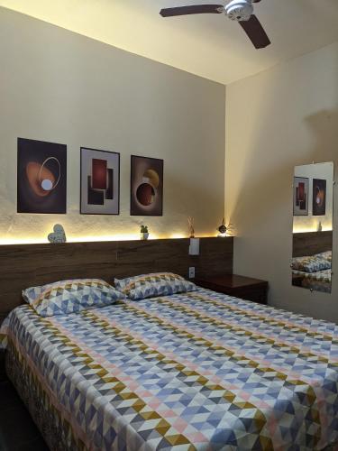 1 dormitorio con 1 cama y algunas fotos en la pared en Região dos Lagos - casa para temporada en São Pedro da Aldeia