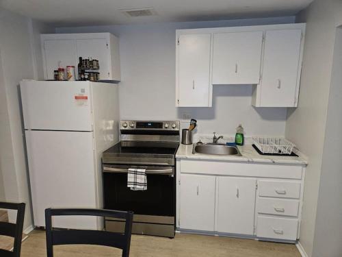 La cuisine est équipée de placards blancs, d'un évier et d'un réfrigérateur. dans l'établissement Cozy and quiet apartment, à Sudbury