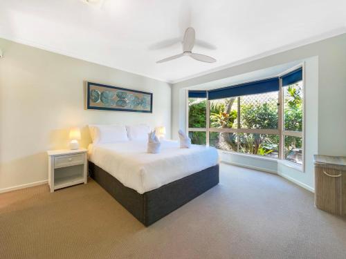 a bedroom with a bed and a large window at Bokarina Family Pet Friendly Holiday Home in Kawana Waters