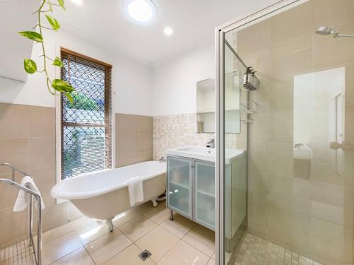 a bathroom with a tub and a sink and a shower at Bokarina Family Pet Friendly Holiday Home in Kawana Waters