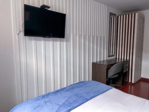 1 dormitorio con cama, escritorio y TV en la pared en Apto tipo loft ubicado en Normandia, en Bogotá