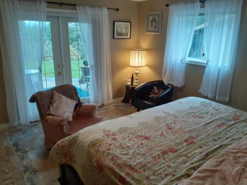 a bedroom with a bed and a chair and windows at Rae Leigh Heights BnB in Saanichton