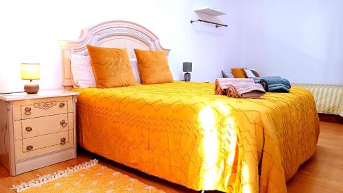 a bedroom with a bed with a yellow bedspread at No centro, junto à Avenida da Liberdade - 1 Drt in Fundão