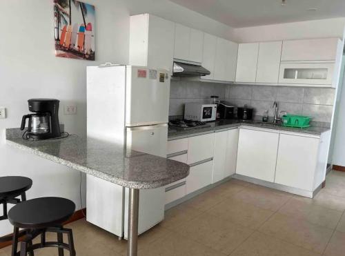 uma cozinha com armários brancos e um frigorífico branco em Apartamento exclusivo Familiar 306 em San Bartolo