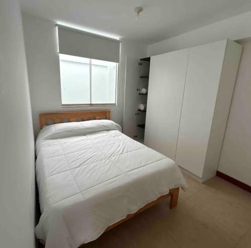 um quarto com uma cama branca e uma janela em Apartamento exclusivo Familiar 306 em San Bartolo
