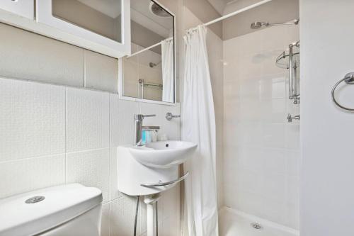 a white bathroom with a sink and a shower at Comfy Studio near Gabba with Secure Parking in Brisbane