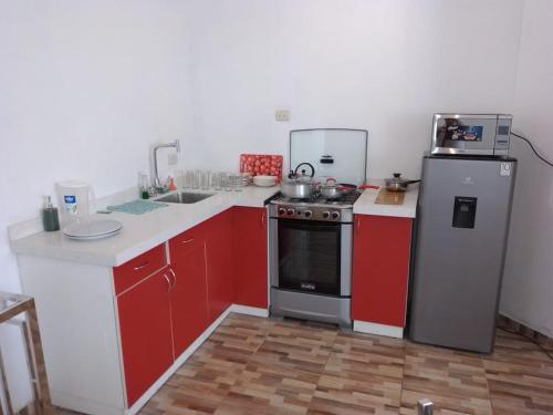 eine Küche mit roten Schränken, einem Herd und einem Kühlschrank in der Unterkunft Departamento centrico de lujo en Huancayo in Huancayo