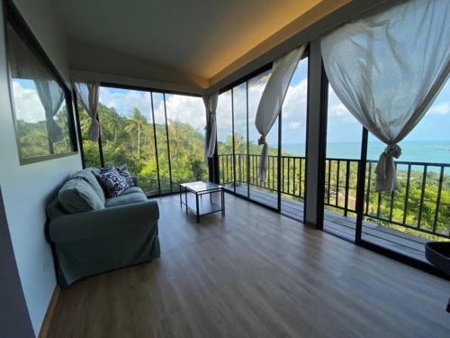 a living room with a couch and a view of the ocean at Ozone Hill Panoramic Residence Thong Nai Pan Beach in Thong Nai Pan Noi