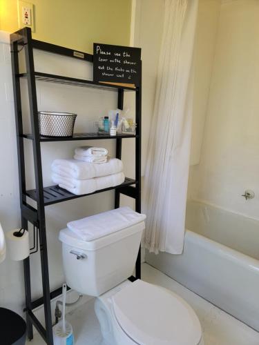 a bathroom with a toilet and a shelf with towels at The Kings Throne Inn and Guest House in Toledo