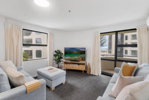 a living room with two couches and a tv at Beach Views at Oceanside in Mount Maunganui