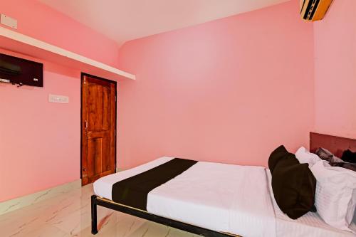 a bedroom with a bed in a pink wall at OYO MAA BHUASUNI RESIDENCY in Cuttack