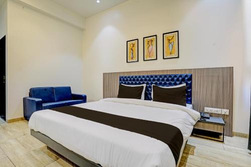a bedroom with a large bed and a blue chair at FabHotel Global Spaces in Mumbai
