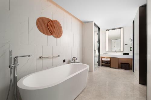 a bathroom with a white tub and a sink at Hampton by Hilton Foshan Beijiao in Foshan