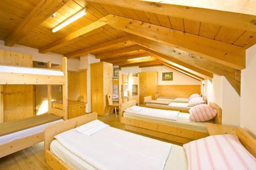 a room with three beds and wooden ceilings at Mahlknechthuette Seiseralm in Alpe di Siusi