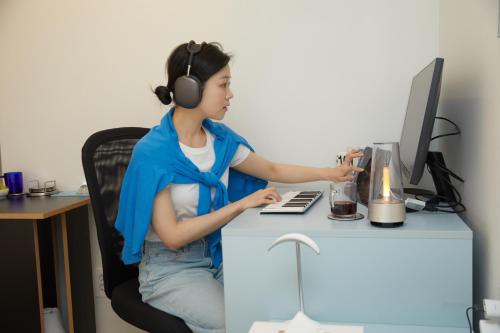 a woman wearing headphones sitting at a desk with a computer at Aank Hotel Seoul Sinchon in Seoul