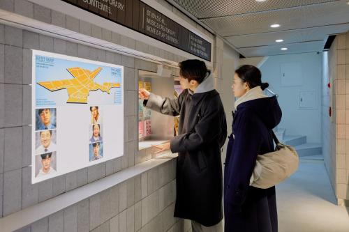 two people looking at a poster on a wall at Aank Hotel Sinchon in Seoul