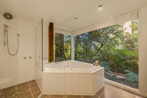 baño grande con bañera y ventana grande en Arnica Views Summit Retreat en Mount Dandenong