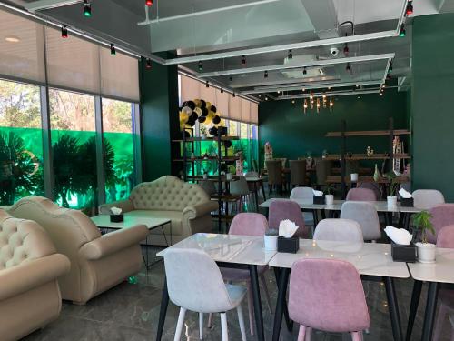 a restaurant with white tables and pink chairs at The Clover Hotel in Angeles