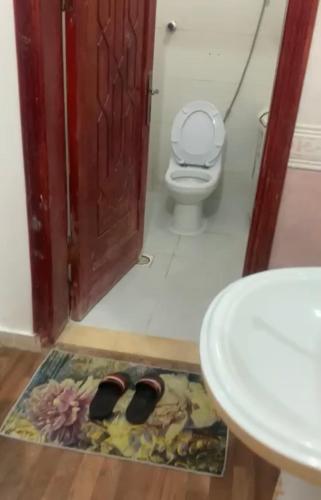 a bathroom with a toilet and a mat in front of a door at شقة1/ في العلا العزيزية بجوار البنك الاهلي in AlUla