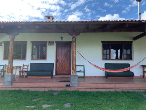 ein Haus mit einer Veranda mit zwei Stühlen und einer Tür in der Unterkunft Hacienda la campiña in Quito
