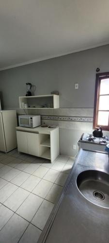 a white kitchen with a sink and a window at Hotel Matos in Capão da Canoa