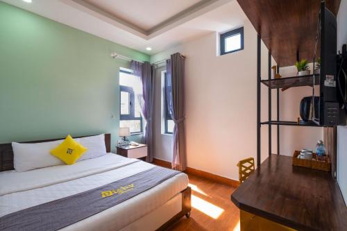 a bedroom with a bed and a desk with a television at Richy Dalat Hotel in Da Lat