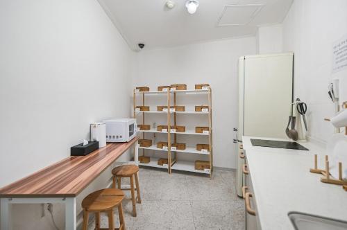 a kitchen with a counter with stools and a refrigerator at SSH Myeongdong Dongdo Hostel in Seoul