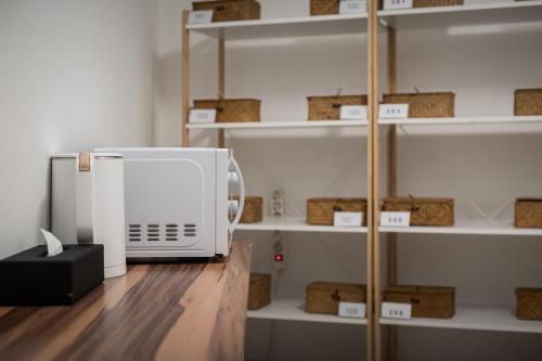 Un microondas colocado encima de un mostrador junto a unos estantes. en SSH Myeongdong Dongdo Hostel, en Seúl