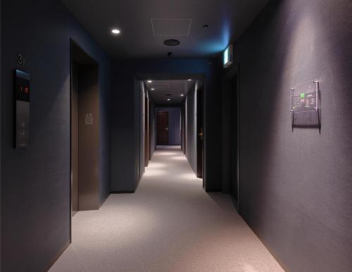 a hallway with blue walls and a long hallway with a hallway at Hotel SUI Kobe Sannomiya by ABEST in Kobe