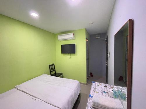 a green room with a bed and a tv at Hotel Global Subang in Subang Jaya