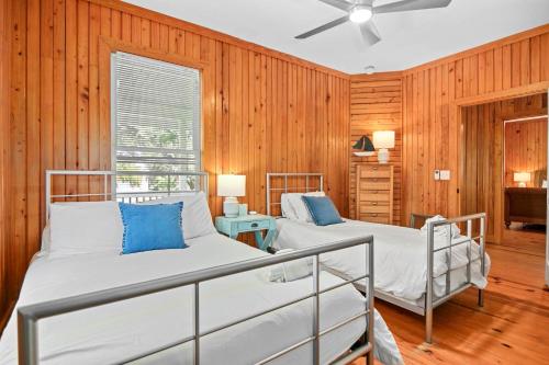 2 camas en una habitación con paneles de madera en Chasing Waves Luxury Edisto Home 3 mins to Beach en Edisto Island