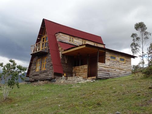 a log cabin with a red roof on a hill at La Teja Experience in Güicán