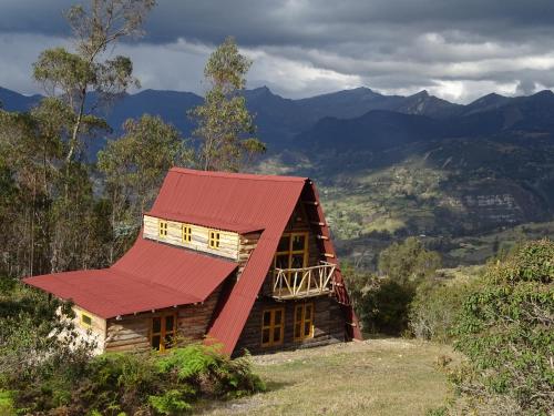 een houten huis met een rood dak op een heuvel bij La Teja Experience in Güicán