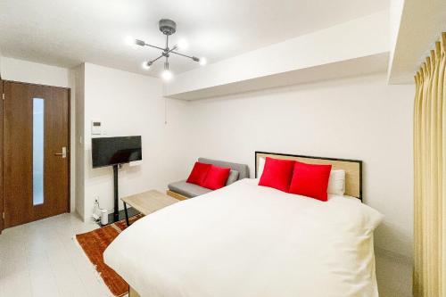 a bedroom with a large white bed with red pillows at Prandre DG in Osaka