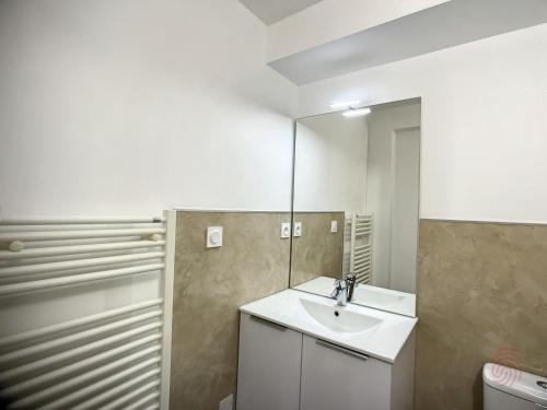 une salle de bain avec un lavabo et un miroir dans l'établissement Charmant F2 avec Terrasse, Proche Thermes et Centre-Ville - Animaux Bienvenus, Wifi Inclus - FR-1-451-205, à Lamalou-les-Bains
