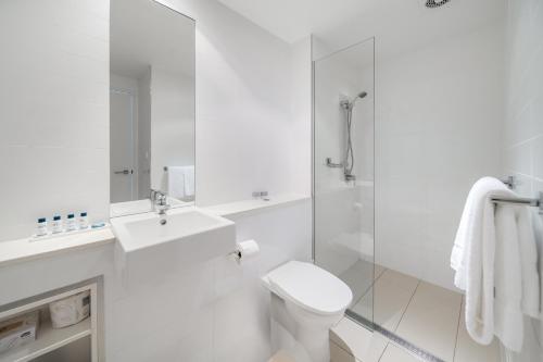 a white bathroom with a toilet and a sink at Oaks Nelson Bay Lure Suites in Nelson Bay