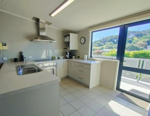 a kitchen with white counters and a large window at Mount Stunner with King Beds in Mount Maunganui